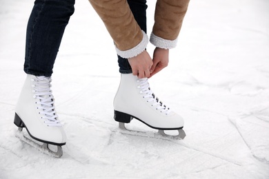 Photo of Woman lacing figure skate on ice rink, closeup
