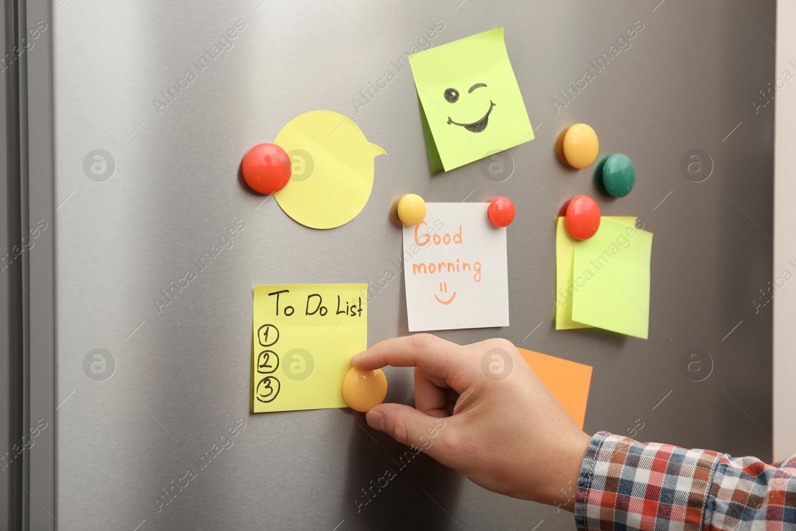 Photo of Man putting paper sheet on refrigerator door, closeup