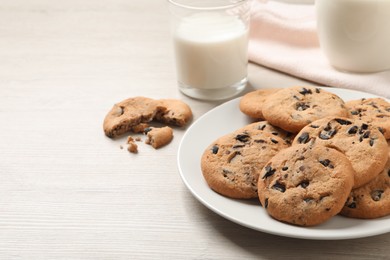 Photo of Plate with delicious chocolate chip cookies on white wooden table. Space for text