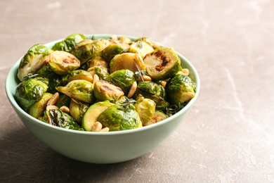 Photo of Delicious roasted brussels sprouts with peanuts on grey marble table, closeup