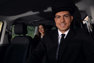Photo of Professional driver and businesswoman in luxury car. Chauffeur service