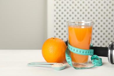 Photo of Tasty shake, orange, dumbbell, measuring tape and powder on white wooden table, space for text. Weight loss