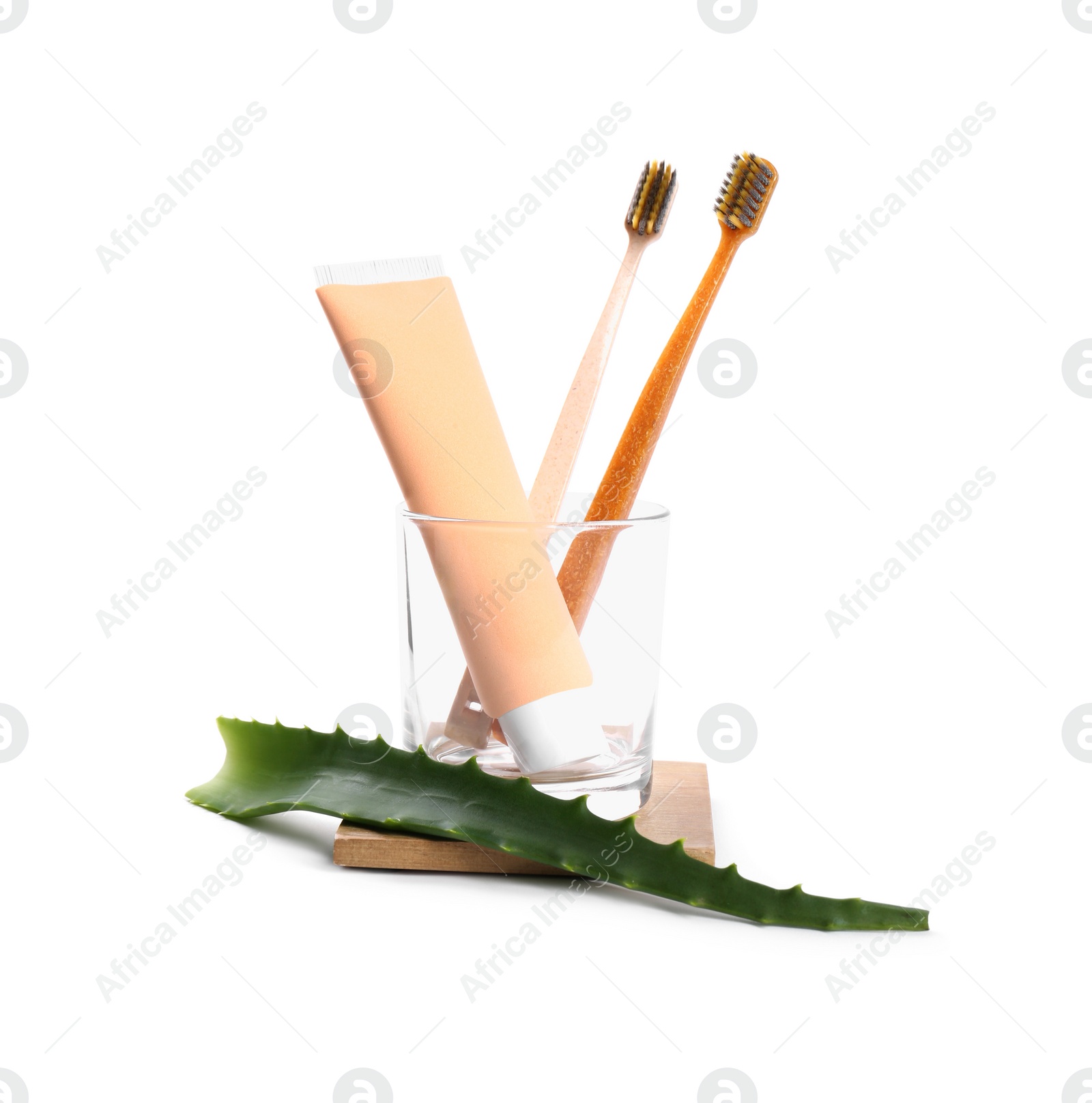 Photo of Tube of toothpaste, brushes and aloe vera leaf on white background