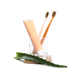 Tube of toothpaste, brushes and aloe vera leaf on white background