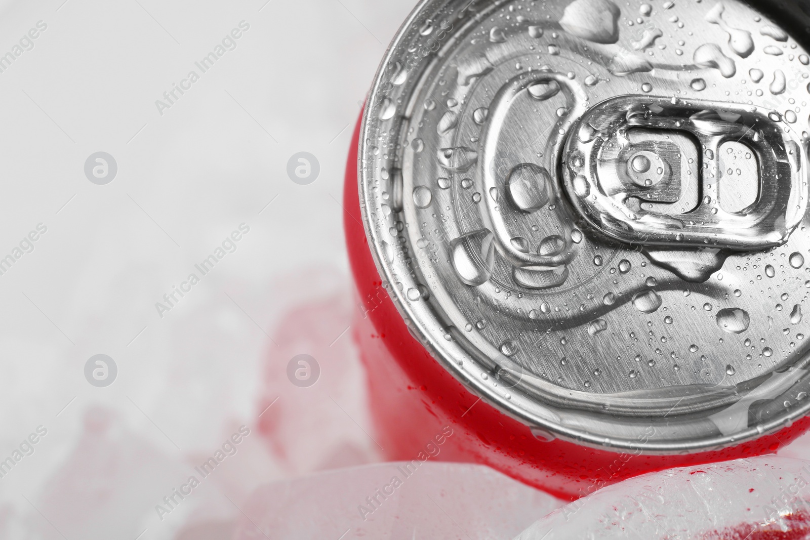 Photo of Energy drink in wet can and ice cubes on light background, closeup. Space for text