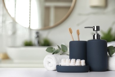 Image of Bath accessories. Different personal care products and eucalyptus leaves on white table in bathroom, space for text