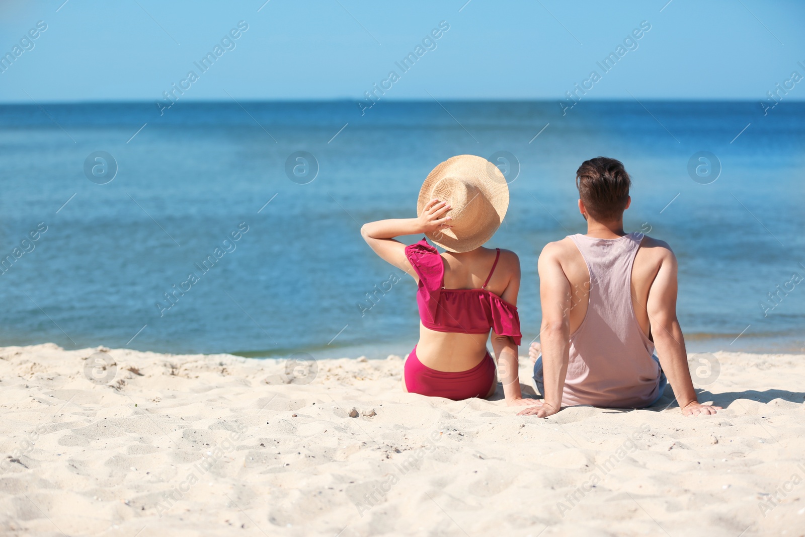 Photo of Happy young couple sitting together at beach on sunny day