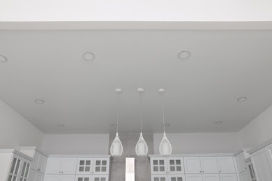 Ceiling with modern lamps and furniture in stylish kitchen
