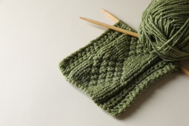 Knitting, soft yarn and needles on beige background, space for text