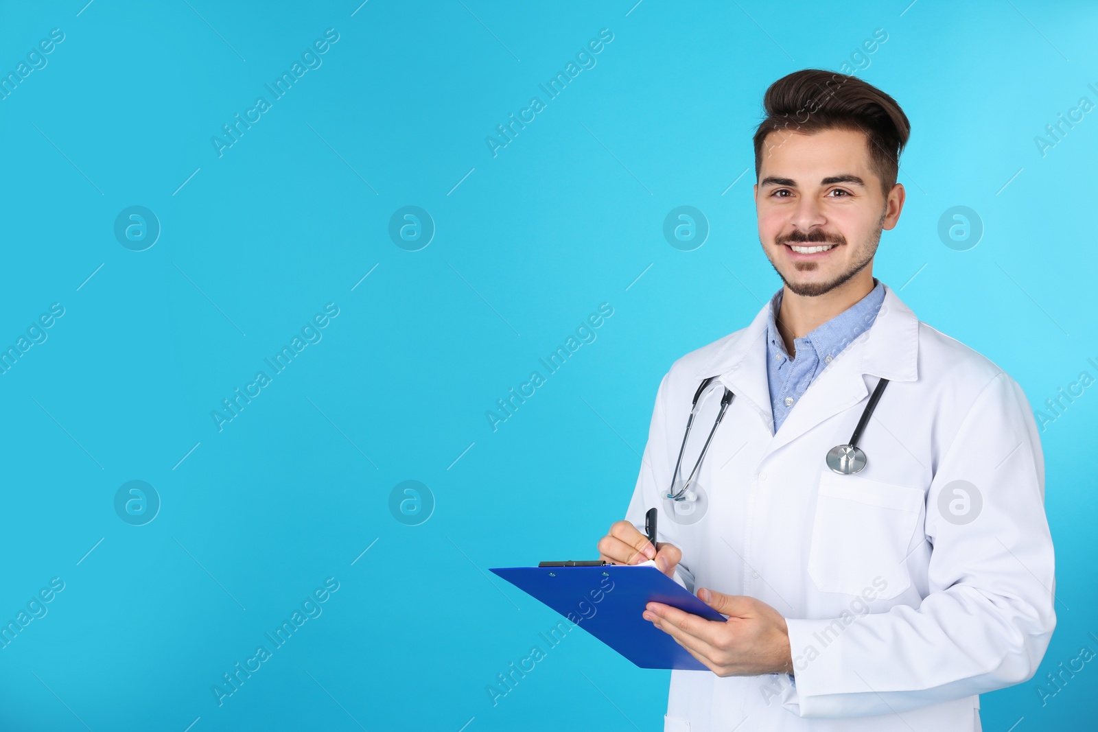 Photo of Young medical student with clipboard on color background. Space for text