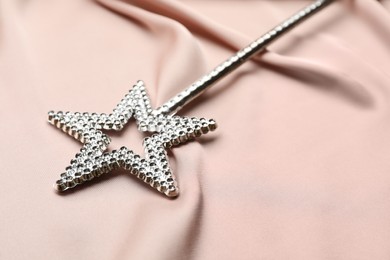 Photo of Beautiful silver magic wand on pink fabric, closeup
