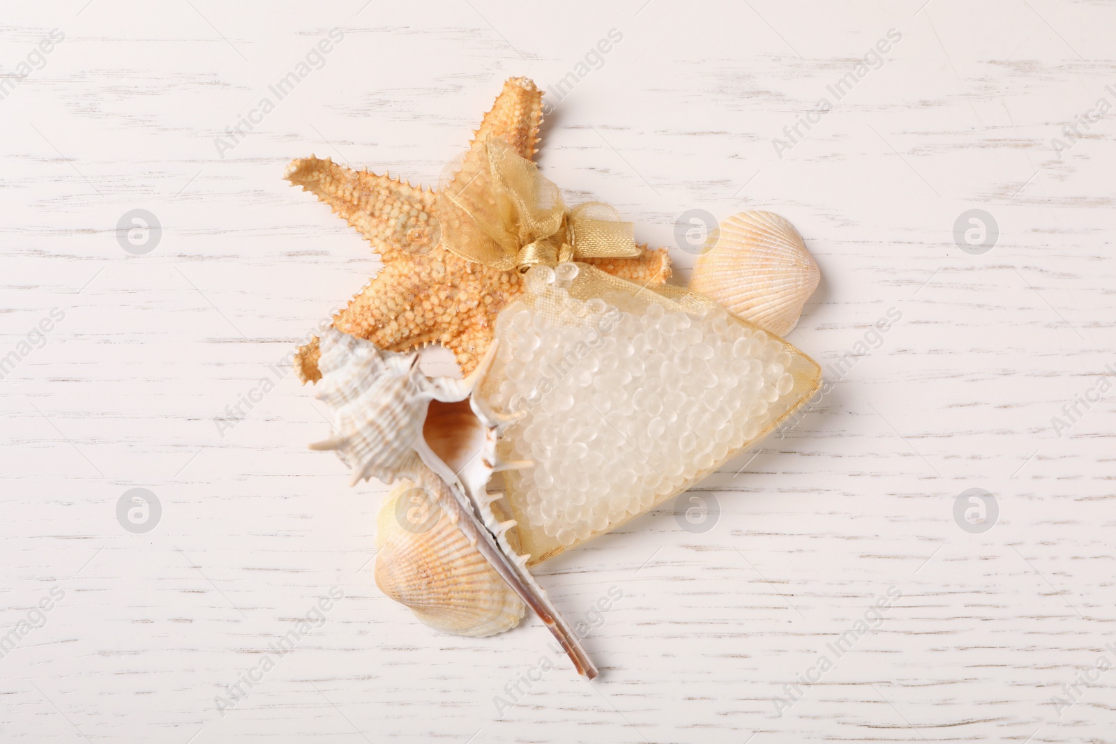 Photo of Scented sachet, starfish and sea shells on white wooden table, flat lay