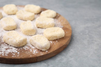 Photo of Making lazy dumplings. Board with cut dough and flour on grey table, closeup. Space for text