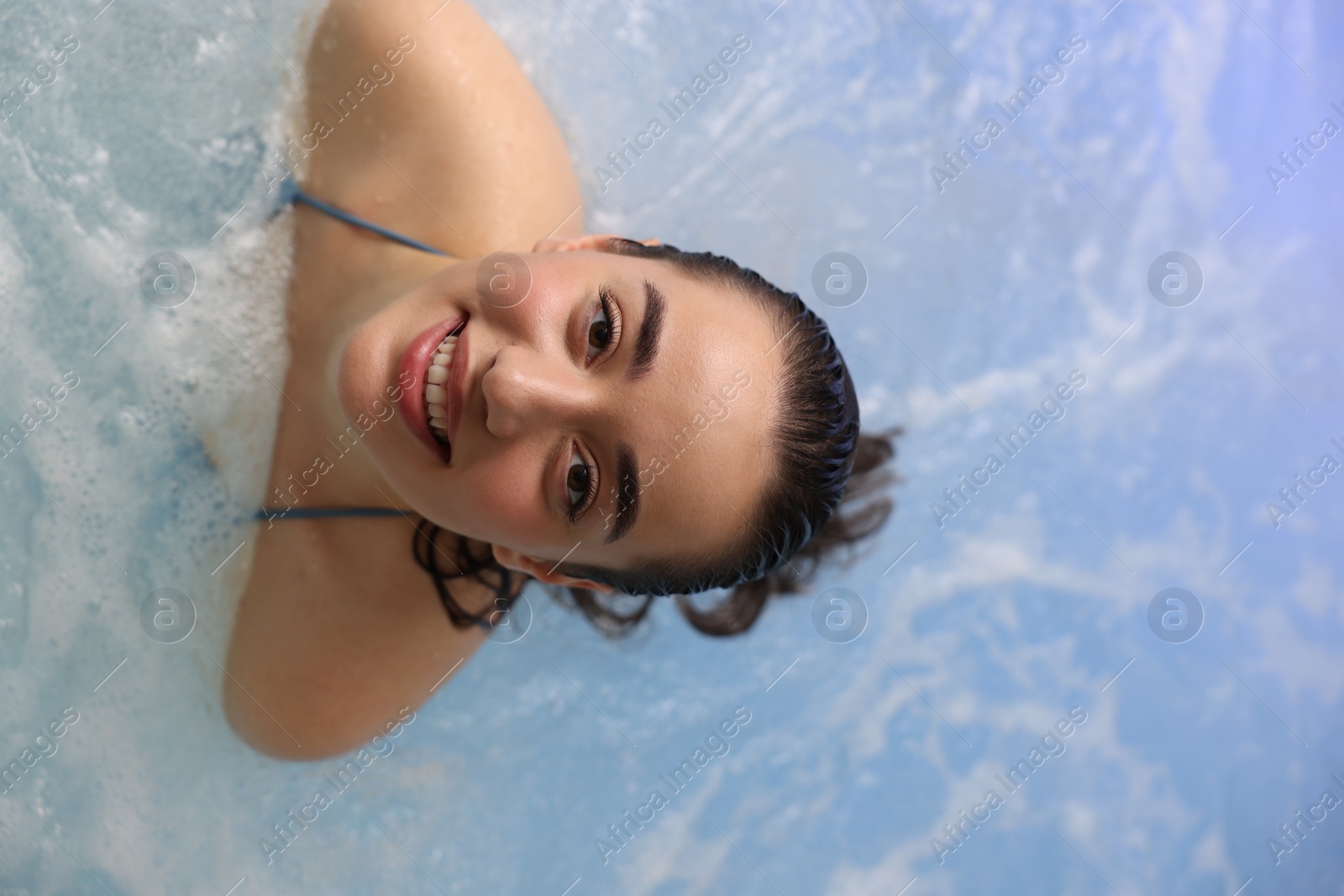 Photo of Beautiful woman relaxing in spa swimming pool, top view