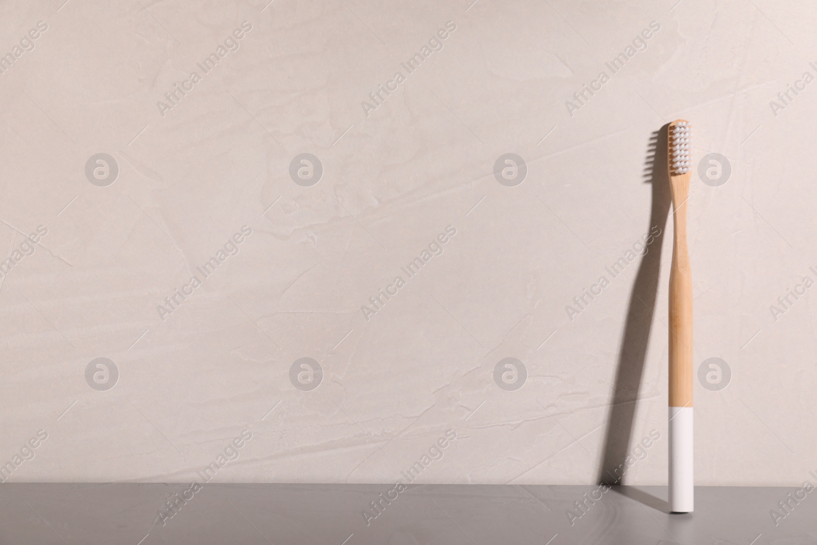 Photo of Bamboo toothbrush on table against grey background. Space for text