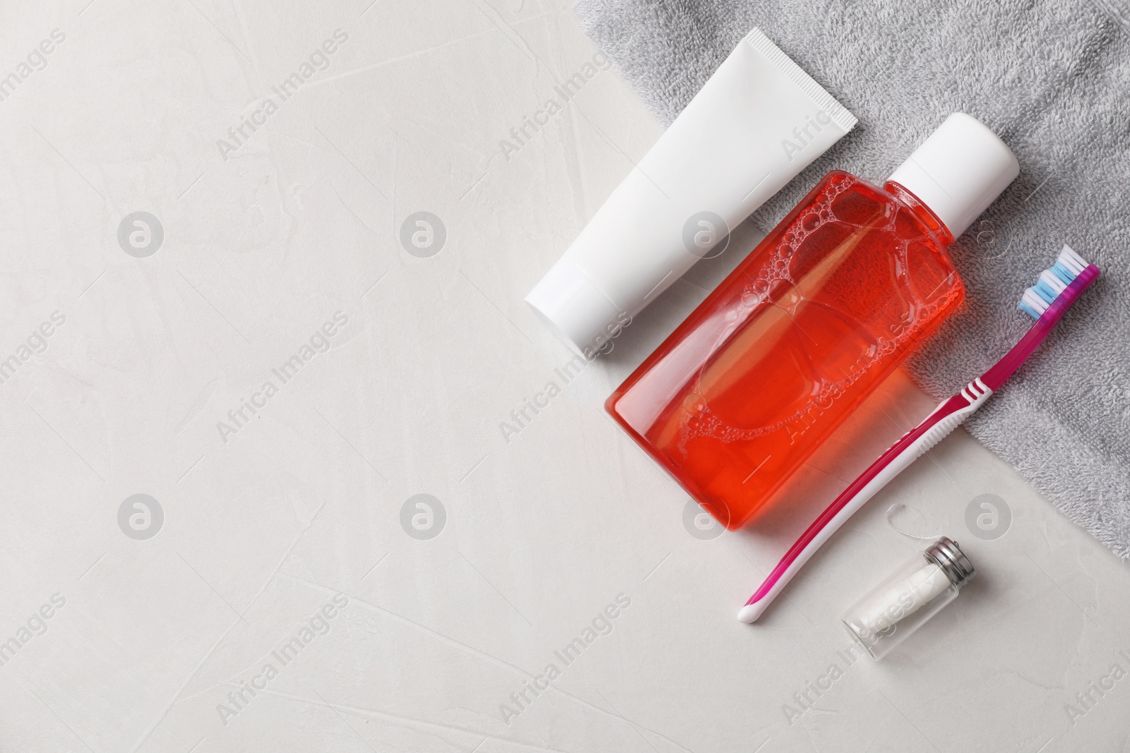 Photo of Fresh mouthwash in bottle, toothpaste, toothbrush and dental floss on light textured background, flat lay. Space for text