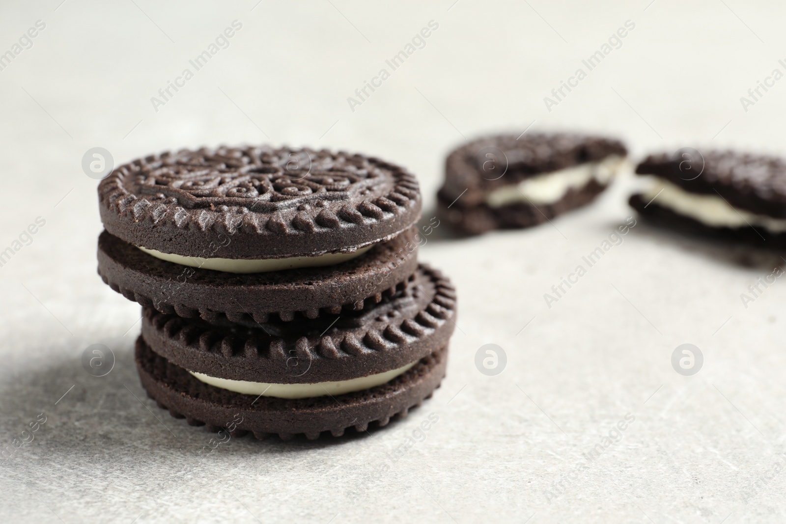 Photo of Tasty chocolate cookies with cream on grey background. Space for text