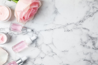 Photo of Flat lay composition with rose essential oil on marble table, space for text