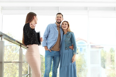 Female real estate agent showing new house to couple, indoors