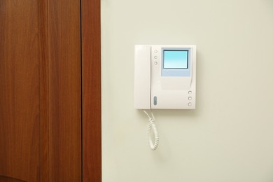 Photo of Modern intercom system with handset on white wall indoors