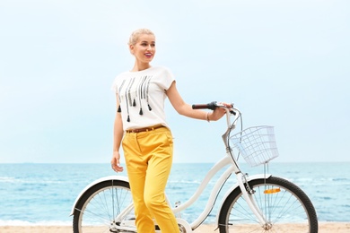 Photo of Beautiful woman in casual outfit with bicycle on sea coast