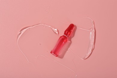 Photo of Skincare ampoule on pink surface with gel, top view