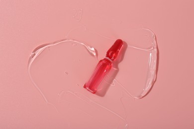 Skincare ampoule on pink surface with gel, top view