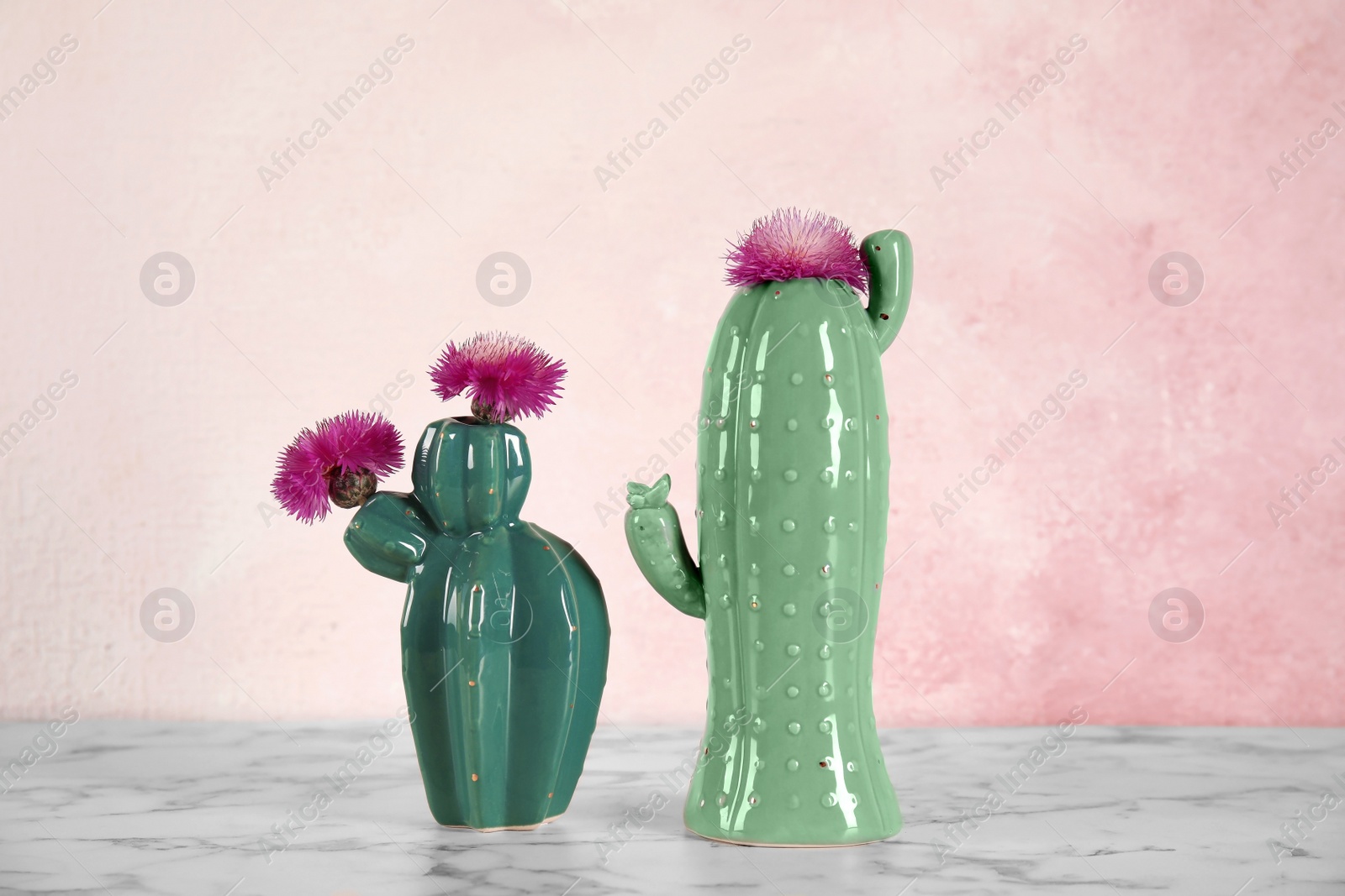 Photo of Trendy cactus shaped ceramic vases with flowers on table