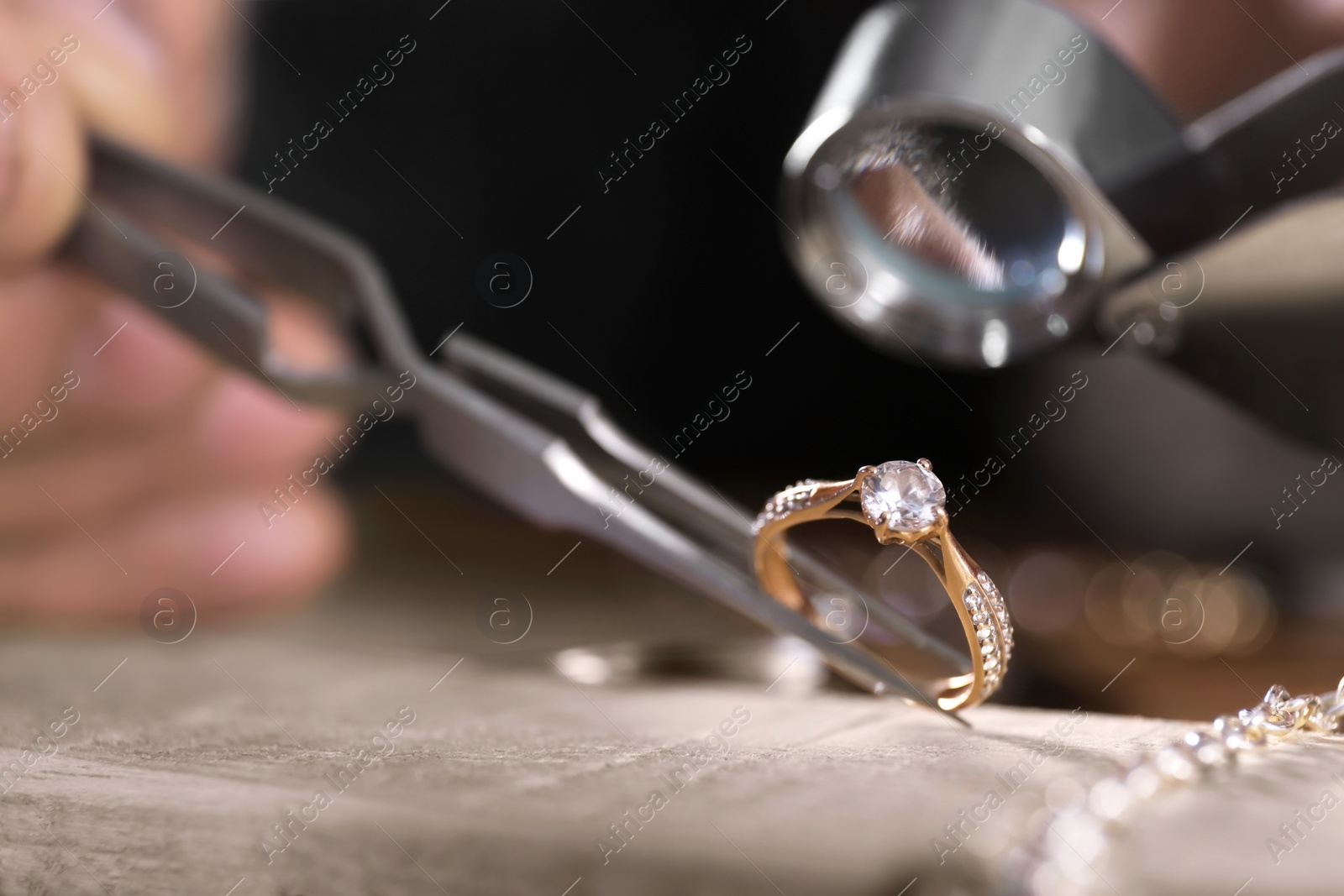 Photo of Male jeweler examining diamond ring in workshop, closeup view