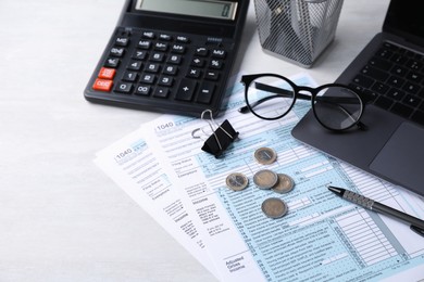 Tax forms, coins, stationery and calculator on light grey table