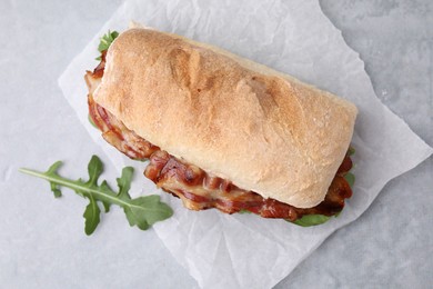 Photo of Tasty sandwich with bacon and arugula on grey table, top view