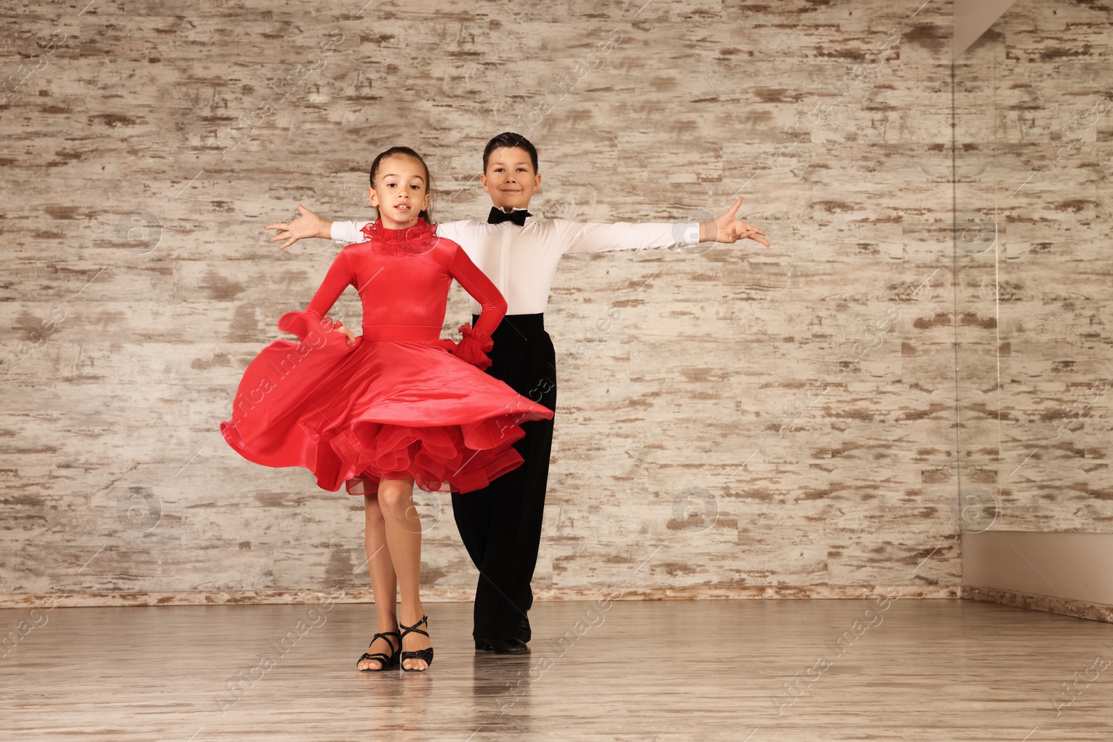 Photo of Beautifully dressed couple of kids dancing together in studio