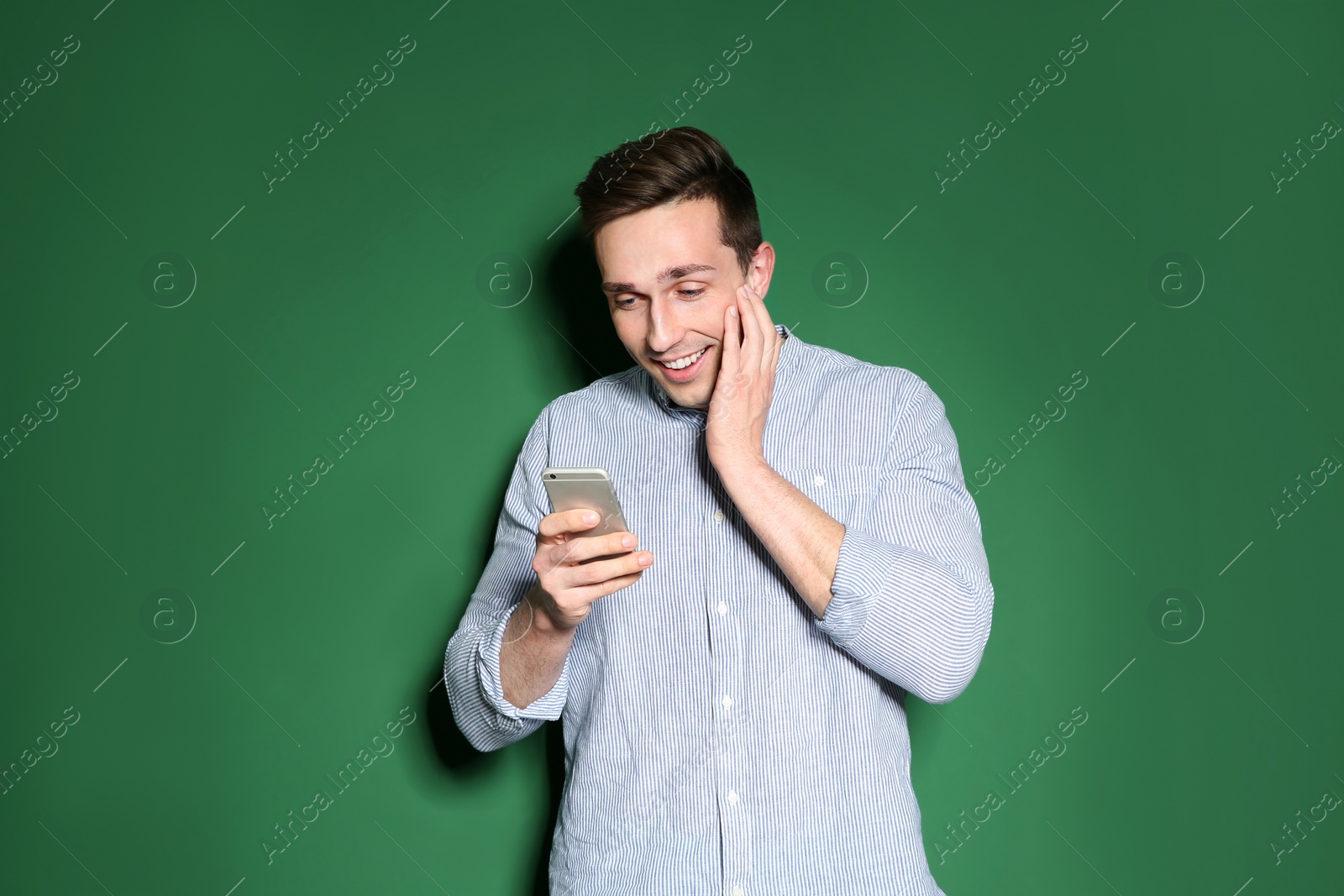 Photo of Portrait of emotional man with mobile phone against color background