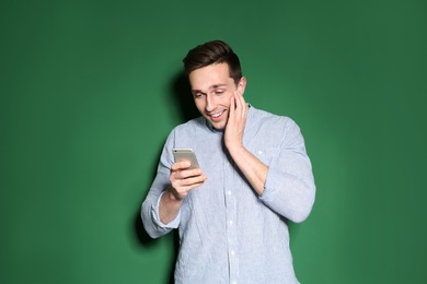 Portrait of emotional man with mobile phone against color background