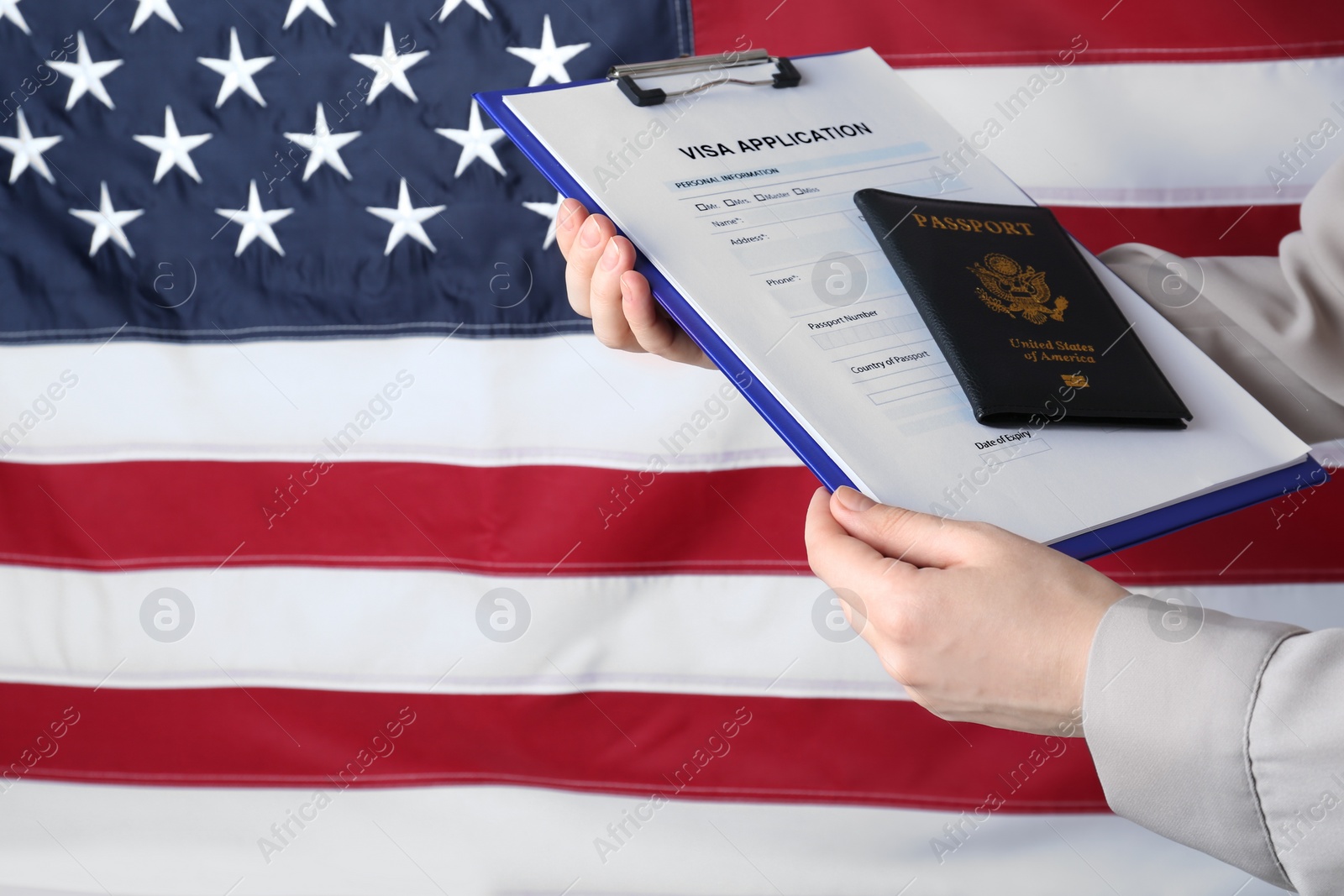 Photo of Woman holding visa application form and passport against American flag, closeup. Space for text