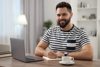 Young man watching webinar at table in room