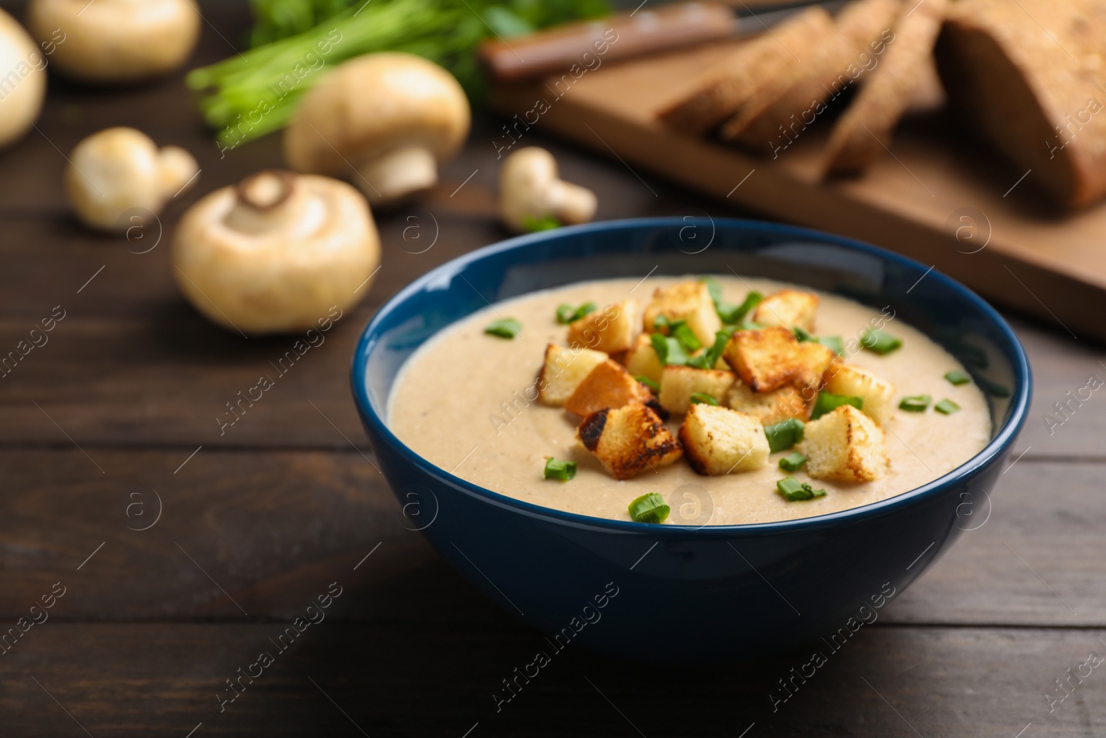 Photo of Bowl of fresh homemade mushroom soup on wooden table