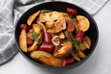 Photo of Delicious baked potato with thin dry smoked sausages, onion and dill in bowl on gray table, closeup