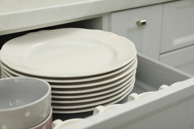 Clean plates and bowls in drawer indoors, closeup