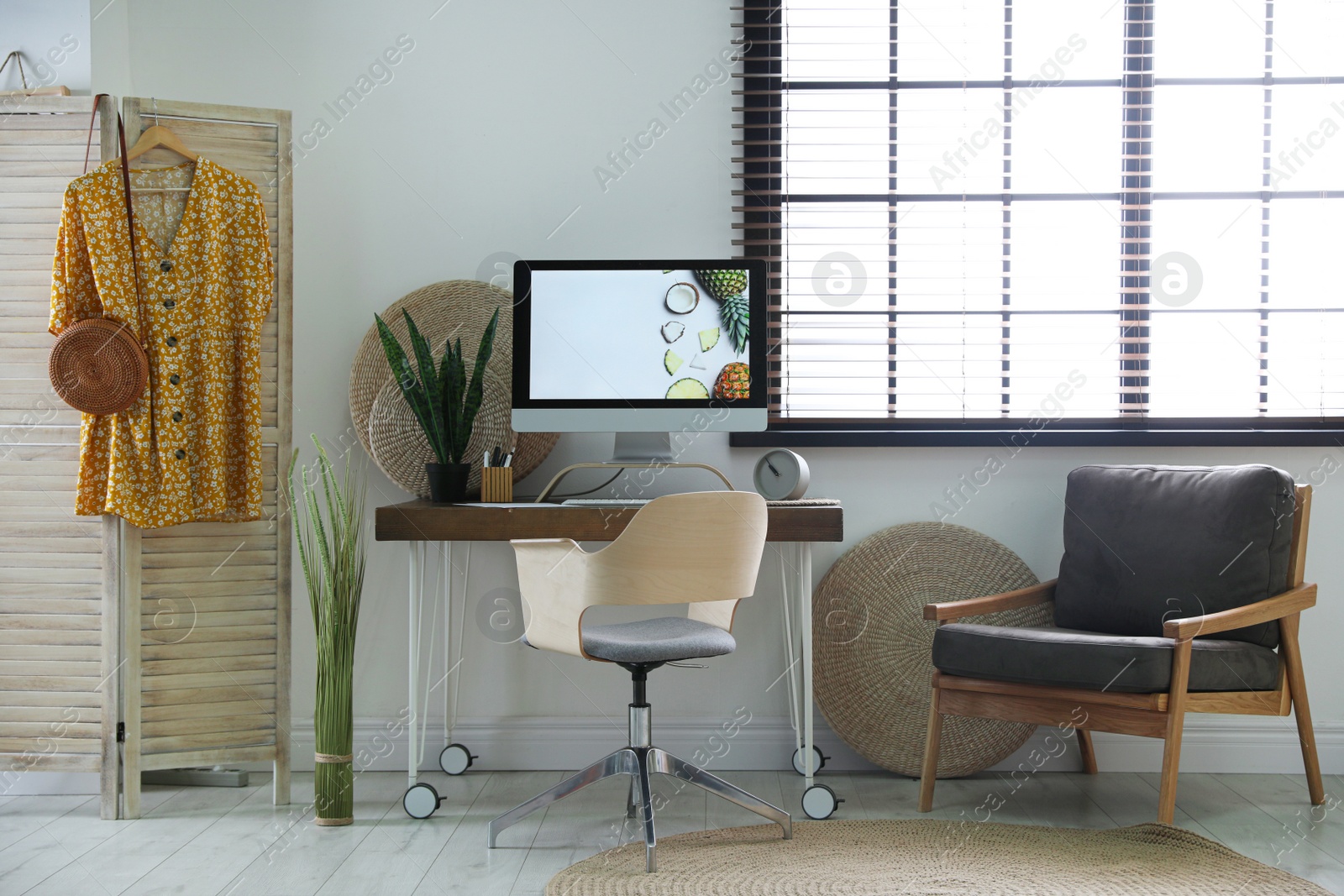 Photo of Comfortable workplace near window with horizontal blinds in room