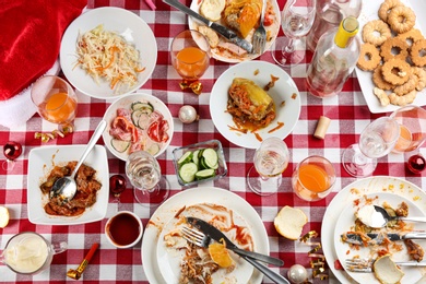 Photo of Flat lay composition of food leftovers after party on table with checkered cloth