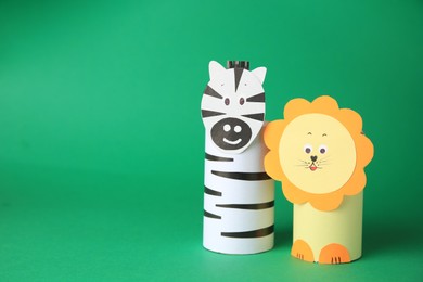 Photo of Toy lion and zebra made from toilet paper hubs on green background, space for text. Children's handmade ideas