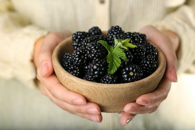 Woman holding bowl of fresh ripe blackberries, closeup