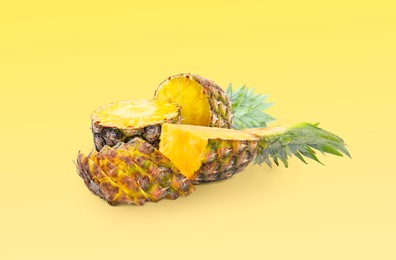 Image of Cut fresh juicy pineapples on yellow background