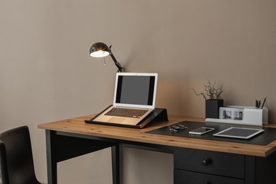 Modern workplace interior with laptop and devices on table. Space for text