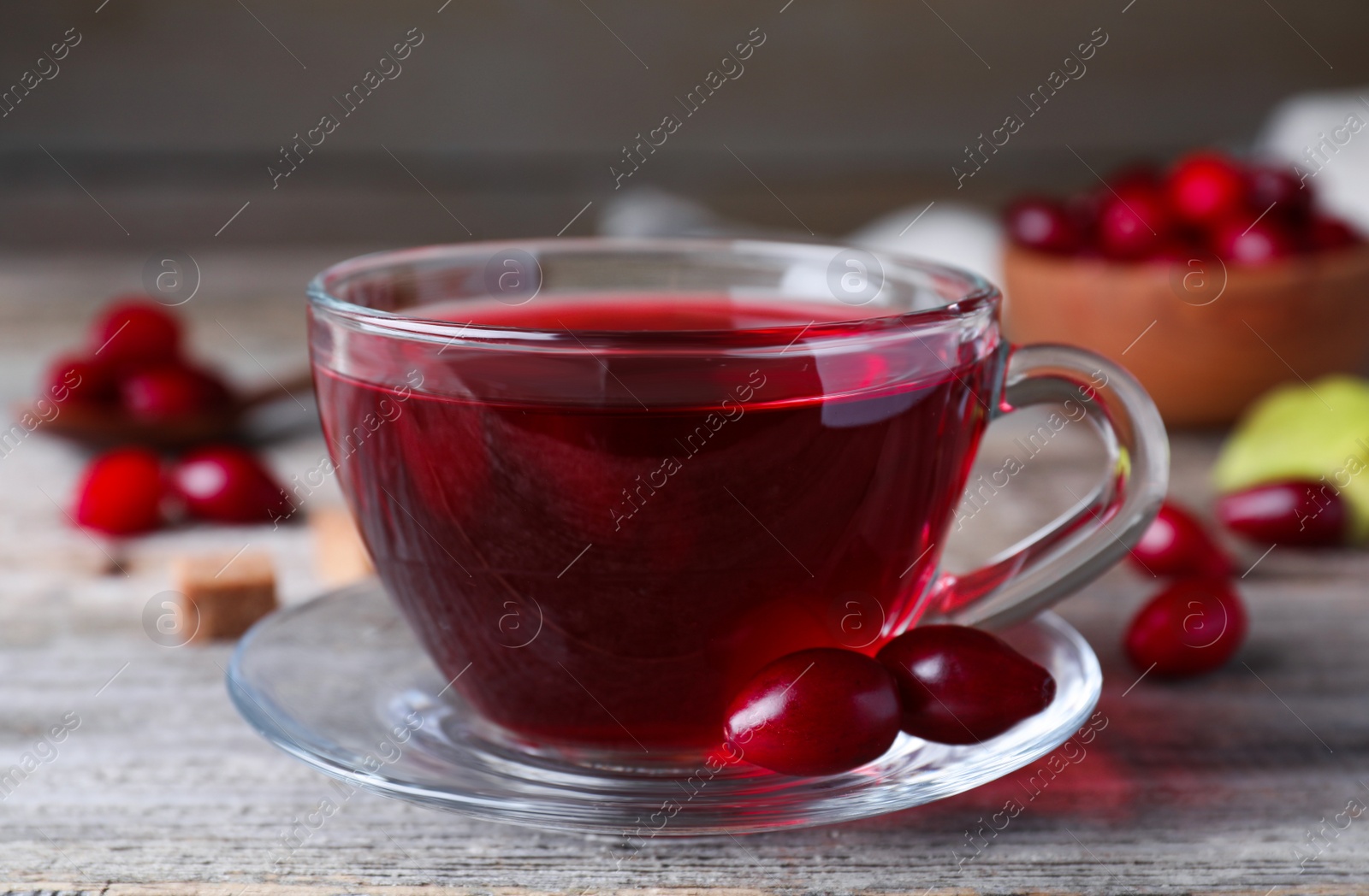 Photo of Fresh dogwood tea and berries on wooden table, closeup