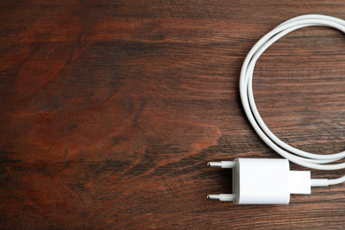 Photo of USB charger on wooden table, top view. Space for text