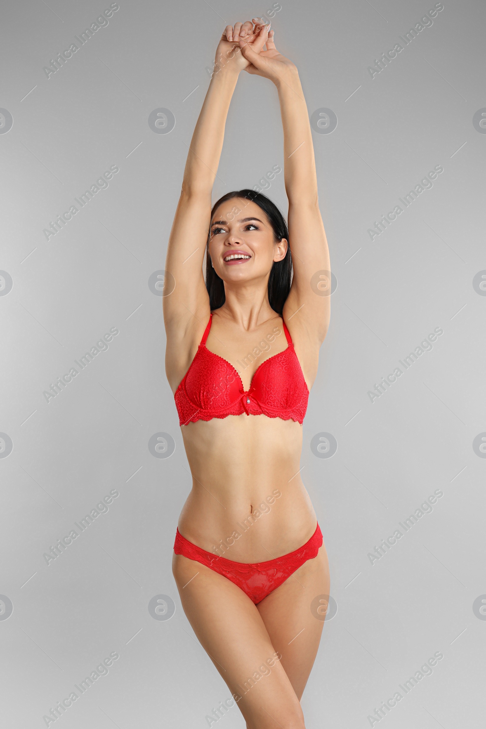 Photo of Beautiful young woman in red underwear on grey background