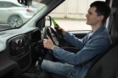 Photo of Smiling man with bottle of beer driving car. Don't drink and drive concept