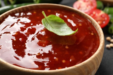 Spicy chili sauce with basil in bowl, closeup